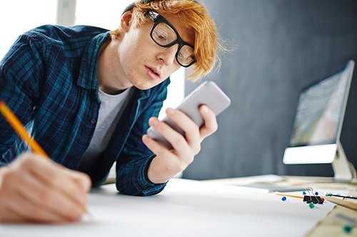 Young man writing sms during work