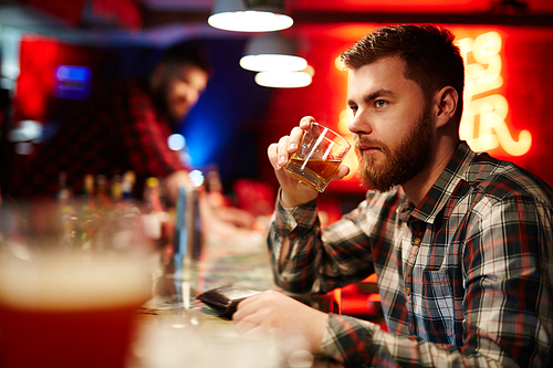 Man sitting and drinking whiskey at bar counter