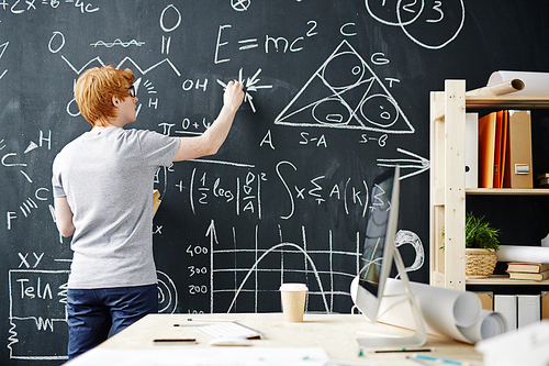 College student writing on the chalkboard during a math class