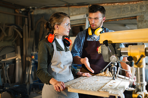Two young woodworkers interacting in workshop