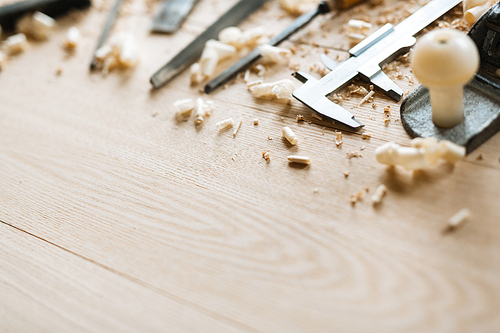 Row of carpentry tools and sawdust on wooden background