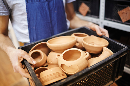 Box with just made earthenware held by potter