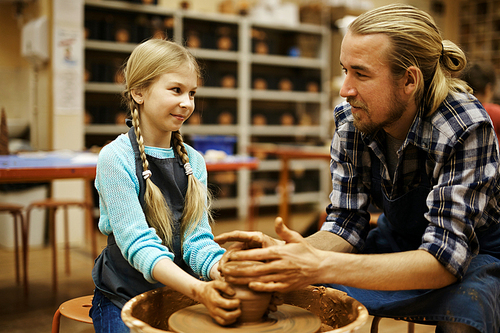 Young man showing his daughter how to make earthenware