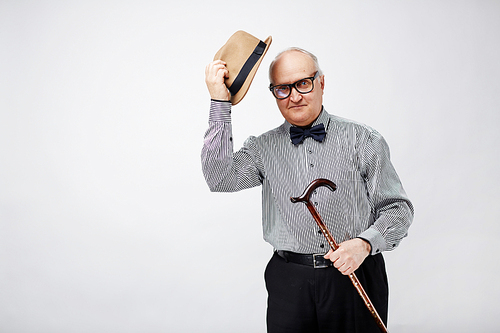 Senior man with cane taking off his hat in greeting gesture