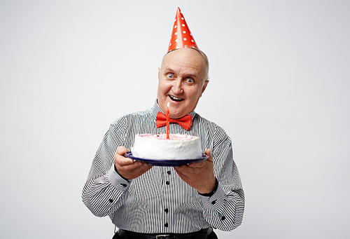 Aged man showing his birthday cake with candle