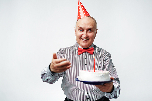 Senior man holding birthday cake with one candle