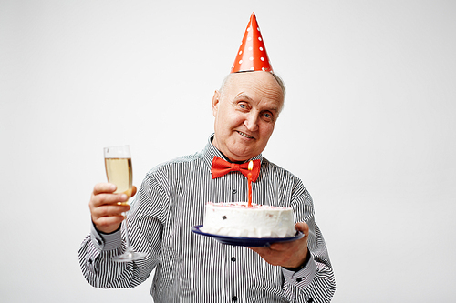 Mature man toasting with champagne and holding birthday cake