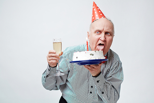 Senior man with birthday cake and flute of champagne having fun at party