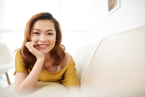 Portrait of attractive Asian girl lying on sofa and 