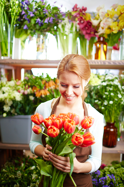 Young florist with flowers working in shop