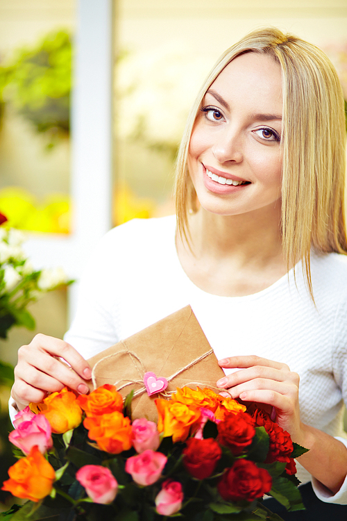 Young woman with love message putting it in floral bouquet