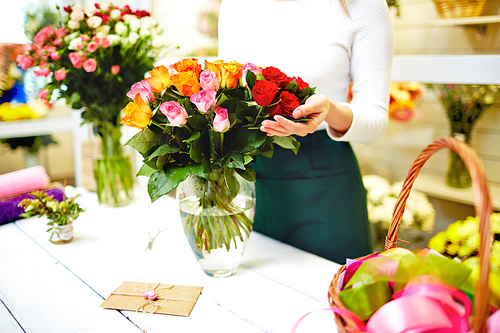 Close-up of female florist standing near the bouquet of roses