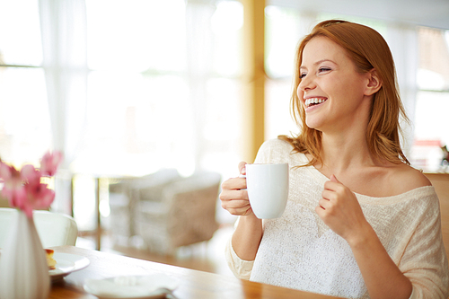 Happy young woman drinking coffee at cafe