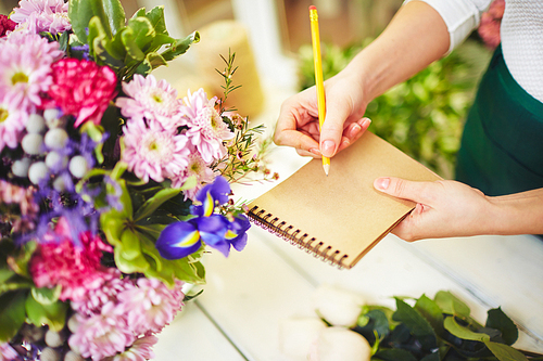 Close-up of florist making notes in notebook