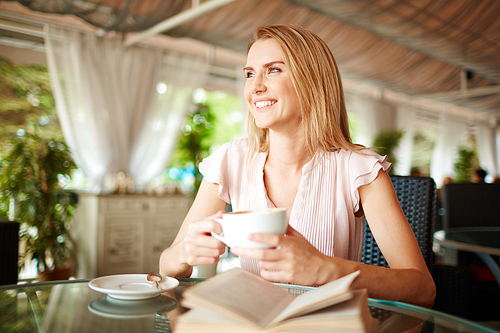 Beautiful girl sitting in cafe and having coffee