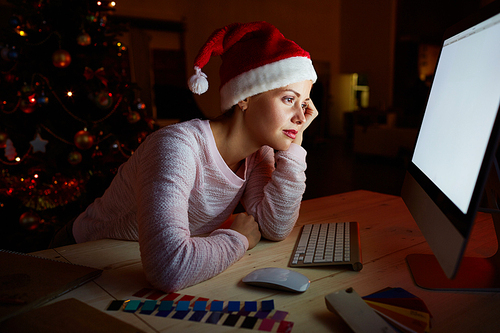 Bored young woman spending xmas night on her own in front of computer