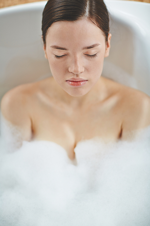 Portrait of a young pretty woman sitting in bath