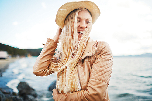 Laughing girl in hat enjoying vacation at the seaside