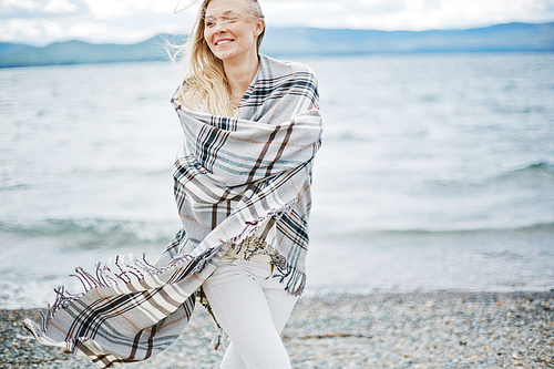 Woman in blanket walking on seaside