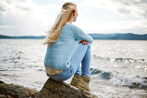 Rear view of young woman sitting on seaside at beach