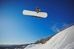 Sporty man on snowboard flying over snowdrift