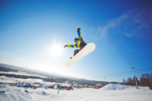 Young sportsman riding on skateboard over winter resort