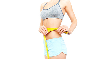 Slim girl measuring her waist isolated on white background