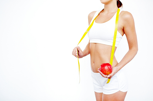 Young slim woman holding a measure tape and an apple isolated on white