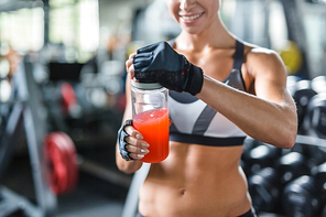 Sporty woman opening bottle with kissel after training