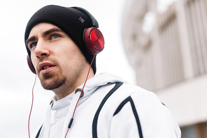 Attractive guy in sportswear listening to music during sport training