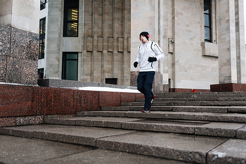Active guy in sportswear running in urban environment