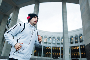 Urban runner training in the city on background of modern edifice