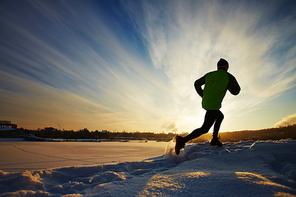 Sportsman jogging in snowdrift in rural environment