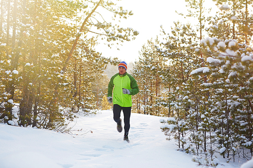 Energetic runner training on winter day in the forest