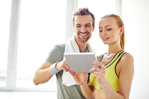 Young sporty couple using touchpad in gym