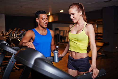 Fit girl and guy in activewear spending time in gym