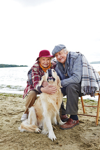 Retired husband and wife and their pet relaxing by seaside