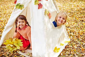Two friendly kids sitting in tent in autumn park