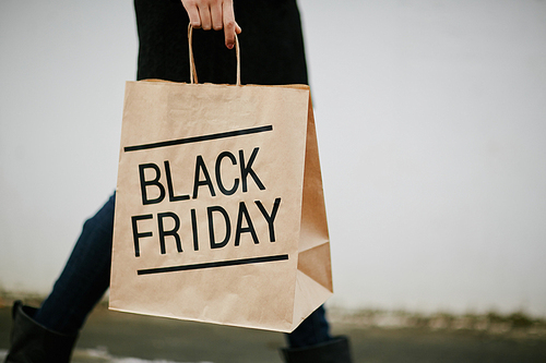 Young woman in black carrying paperbag on Black Friday