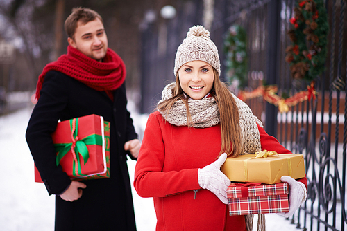 Happy woman with Christmas presents  on background of her husband outdoors