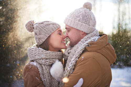 Young amorous couple in winterwear flirting outside