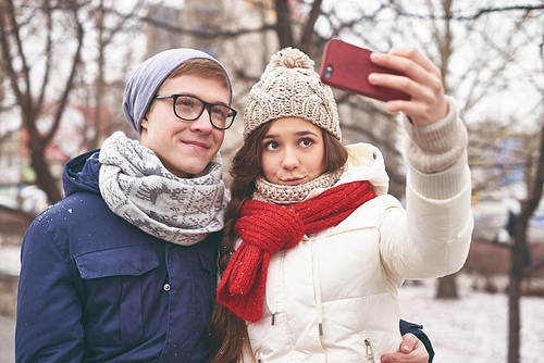 Amorous dates in winter-wear making selfie