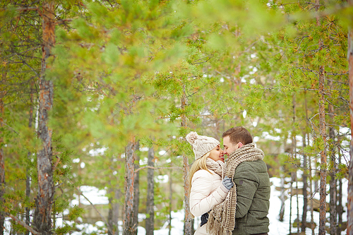 Attractive young couple in winterwear embracing in natural environment