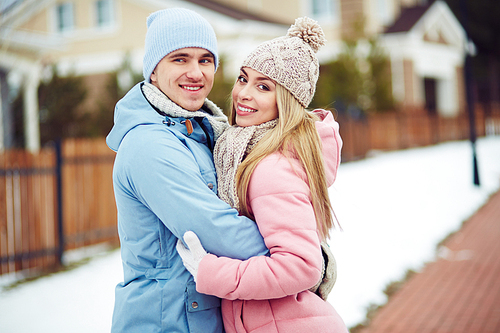 Young dates in winterwear embracing in urban environment