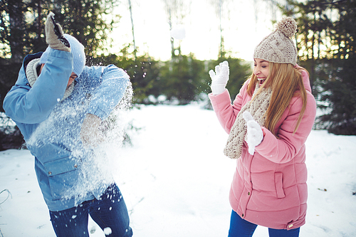 Happy young dates playing snowballs outdoors