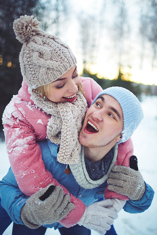 Joyful guy and girl in winterwear having fun