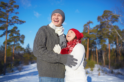 Ecstatic man and woman in knitted winterwear spending leisure in park