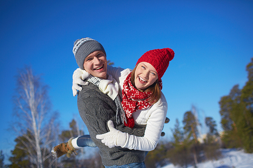 Joyful couple in knitted winterwear having fun outdoors