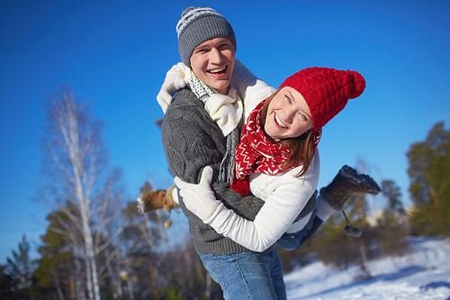 Cheerful girl and guy in knitted winterwear having fun in natural environment
