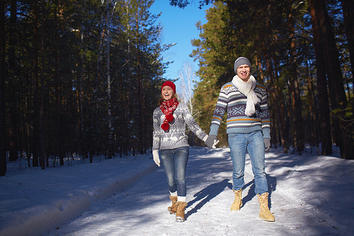 Amorous and ecstatic couple taking walk in winter forest